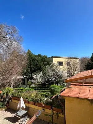 a patio with a table and an umbrella in a garden at Hotel d'Orleans in Palermo