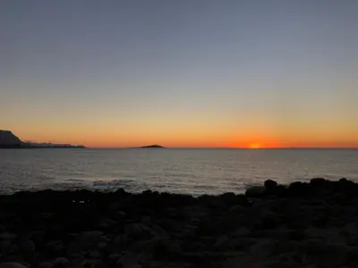 a sunset over the ocean with an island in the distance at Appartamento Green Room in Palermo