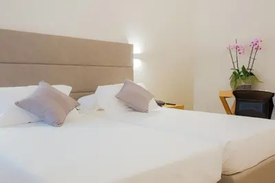 a bedroom with two beds with white sheets and pillows at Hotel Politeama in Palermo