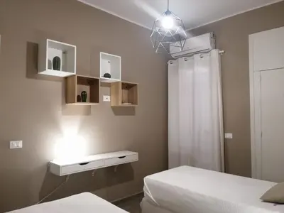 a bedroom with two beds and a light on the wall at Appartamento Corallo in San Vito lo Capo