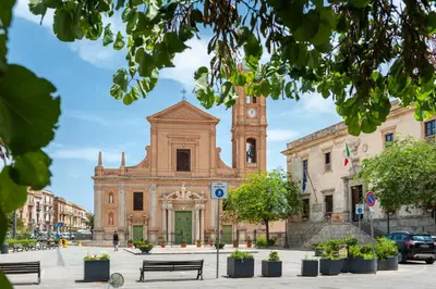 an old building with a clock tower in a city at La Paperella Blu Apartment in Termini Imerese