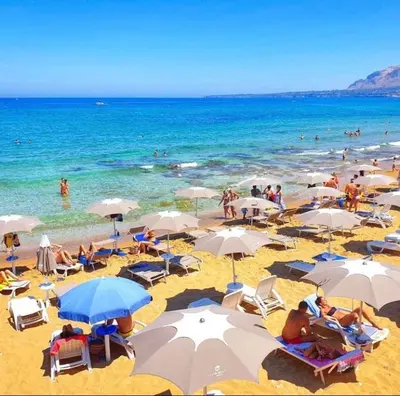 a group of people sitting on a beach with umbrellas at Casa Vacanza Accetta in Trappeto
