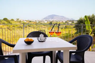 a table with two glasses of wine on a balcony at Villa Arianna, il piacere di vivere nella natura. in Alcamo