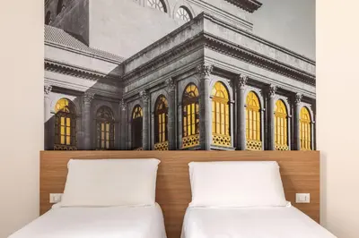 two beds in a room with a painting on the wall at B&B Hotel Palermo Quattro Canti in Palermo