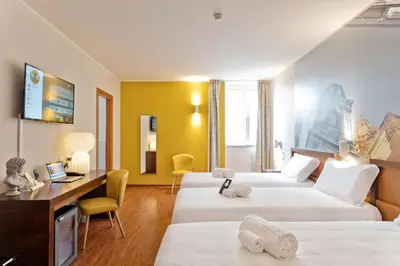 a hotel room with two beds and a desk at B&B Hotel Palermo Quattro Canti in Palermo