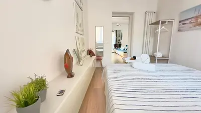 a white bedroom with a bed and a living room at Merlo Holiday Room in Palermo