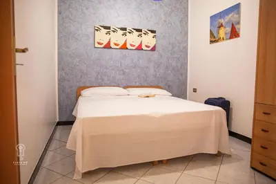 a bedroom with a white bed with two pictures on the wall at CIATU ME' Scirocco in Castellammare del Golfo