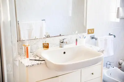 a white bathroom with a sink and a mirror at CIATU ME' Scirocco in Castellammare del Golfo