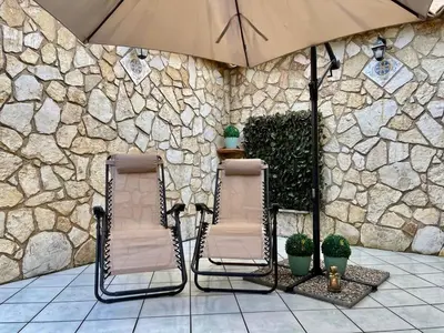 two chairs and an umbrella in front of a stone wall at AMATI HOLIDAYS in Palermo