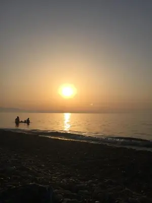 two people in the water at the beach at sunset at AMUNI' Apartments in Trabia