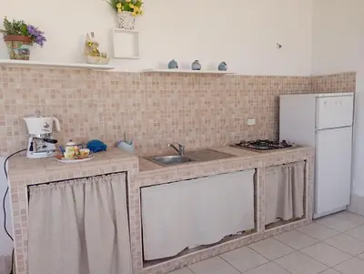 a kitchen with a counter with a sink and a refrigerator at Casa bluchic Gioisia in Isola delle Femmine
