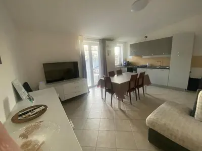 a kitchen and living room with a table and a television at Casavacanze Alba in Alcamo