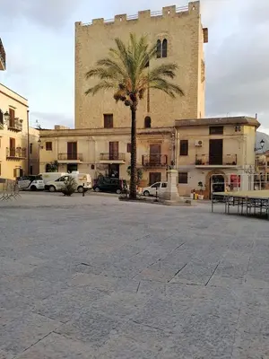 a large building with a palm tree in a parking lot at Casa di Lia in Montelepre