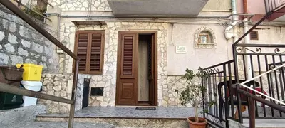 a building with a wooden door and a staircase at Casa di Lia in Montelepre
