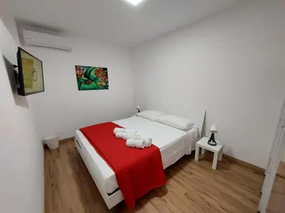 a bedroom with a white bed with a red blanket at Al cortiletto in Castellammare del Golfo