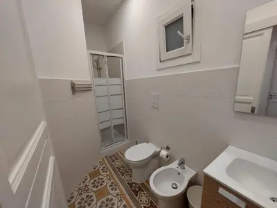 a white bathroom with a toilet and a sink at Al cortiletto in Castellammare del Golfo