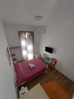 a small room with a pink bed and a window at Al cortiletto in Castellammare del Golfo