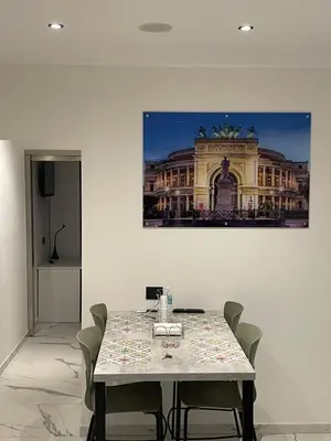 a table with chairs and a picture of a building at Casa vacanze donna Pina in Palermo