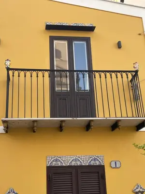 a yellow building with a balcony with a window at Casa vacanze donna Pina in Palermo