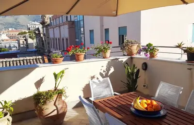 a table and chairs on a balcony with plants at [TERRACE WITH VIEW] Attic in old town BallarHome in Palermo