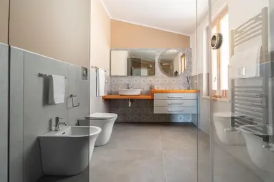 a bathroom with two toilets a sink and a mirror at Villa vista mare con piscina riscaldata a Trappeto in Balestrate