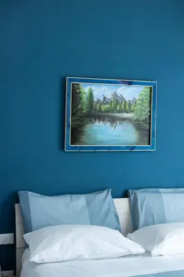 a painting on a blue wall above a bed at PalerMonAmour Art Gallery Suite in Palermo