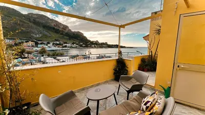 a balcony with chairs and tables and a view of the water at La casetta al mare in Palermo