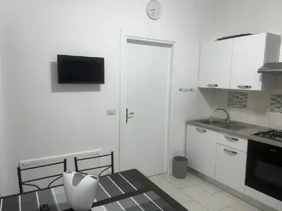 a kitchen with white cabinets and a door with a television at The traveler's house in Palermo