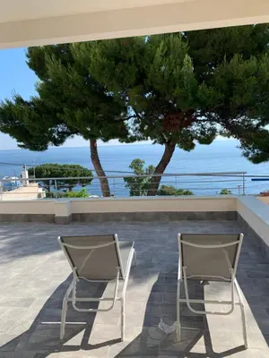 two chairs sitting on a patio looking out at the ocean at Mondello Addaura Addisio Suite in Palermo