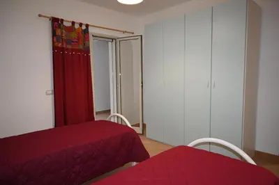 a bedroom with two beds and a red curtain at Chalet Calarossa in Terrasini