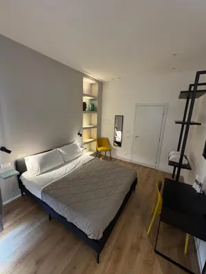 a bedroom with a large bed and a yellow chair at Mori's Rooms in Palermo