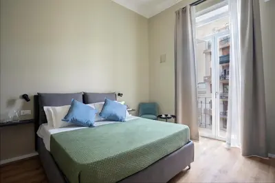 a bedroom with a bed with blue pillows and a window at Mori's Rooms in Palermo