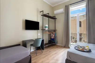 a room with a bed and a desk with a television at Mori's Rooms in Palermo