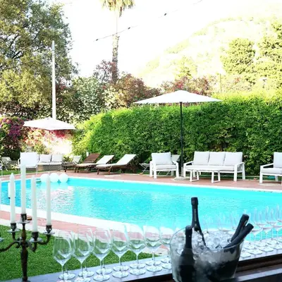 a table with wine glasses next to a swimming pool at Villa Losanna in Mondello