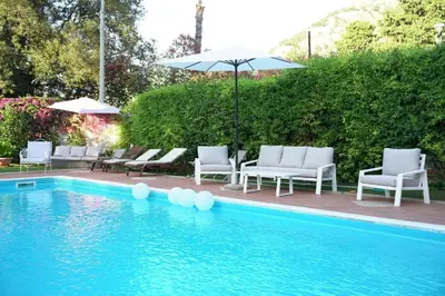 a swimming pool with chairs and an umbrella and an umbrella at Villa Losanna in Mondello