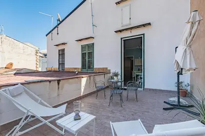 a patio with white chairs and an umbrella at GuestHost - Terry's Garden in Palermo in Palermo