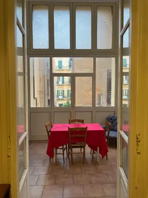 a dining room with a table and chairs and windows at Nowhere Rooms in Palermo