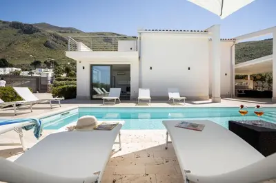 a swimming pool with two chairs and a house at Grande Villa privata con piscina a Scopello in Castellammare del Golfo