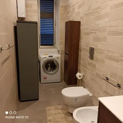 a bathroom with a toilet and a washing machine at Lilibet Apartment in Palermo