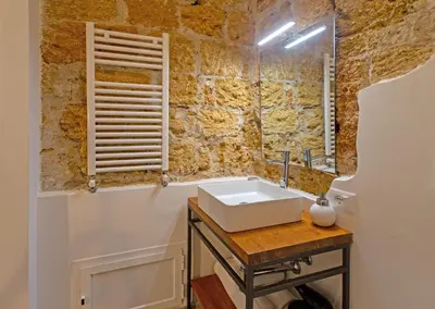 a bathroom with a sink and a stone wall at Isula in Palermo