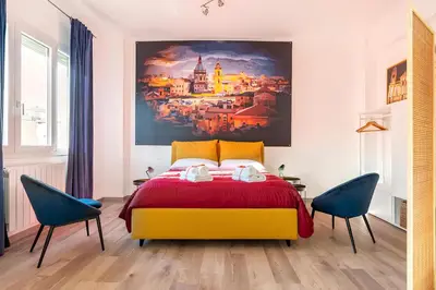 a bedroom with a yellow bed and two blue chairs at Ai Tesori di Palermo in Palermo