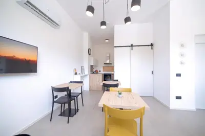 a kitchen and dining room with white walls and yellow chairs at Ciuri' Affittacamere in Alcamo