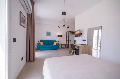 a bedroom with a white bed and a blue couch at Ciuri' Affittacamere in Alcamo