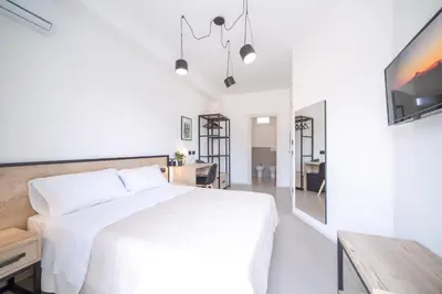 a white bedroom with a bed and a dining room at Ciuri' Affittacamere in Alcamo
