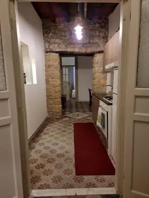 a hallway leading to a kitchen with a stone wall at Domus Sant'Anna Apartment in Palermo