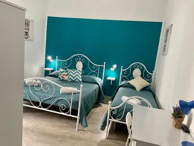 a bedroom with two beds and a blue wall at Casa Vittoria in Palermo