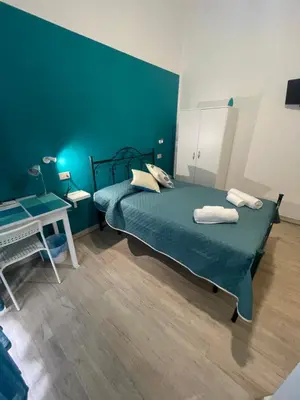 a blue bedroom with a bed and a desk at Casa Vittoria in Palermo