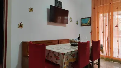 a dining room with a table and chairs and a television at Casa Zibè in Isola delle Femmine