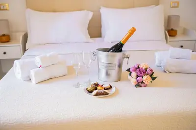 a bottle of wine and a plate of food on a bed at AUSA suites in Palermo