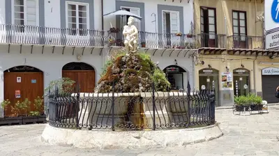 a statue of a woman holding an umbrella on a fountain at AUSA suites in Palermo